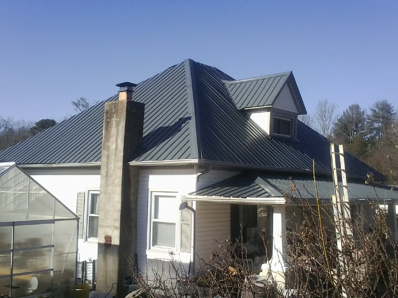 Dark blue standing seam metal roof on a white farmhouse with dormer — Slate & Tile Roof Repair by Roofing Brothers in Haswell