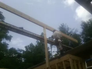 Carpenter setting a ridge beam over a new addition frame — Ice Dam Removal by Roofing Brothers in Haswell