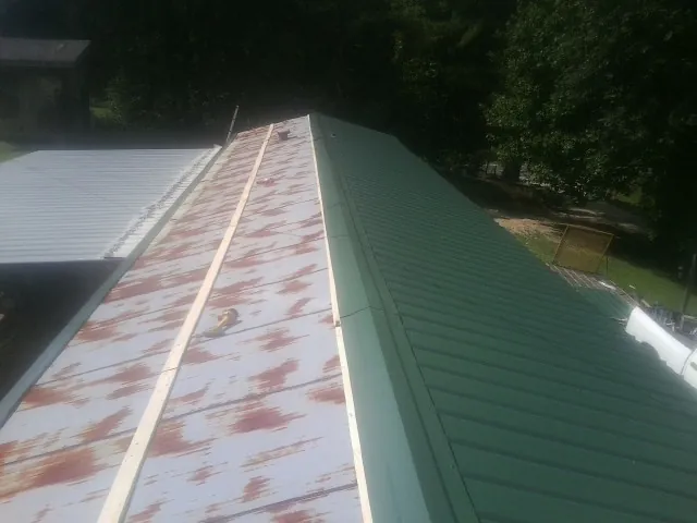 Old rusted panels beside newly installed green metal roofing — Wind Damage Roof Repair by Roofing Brothers in Haswell