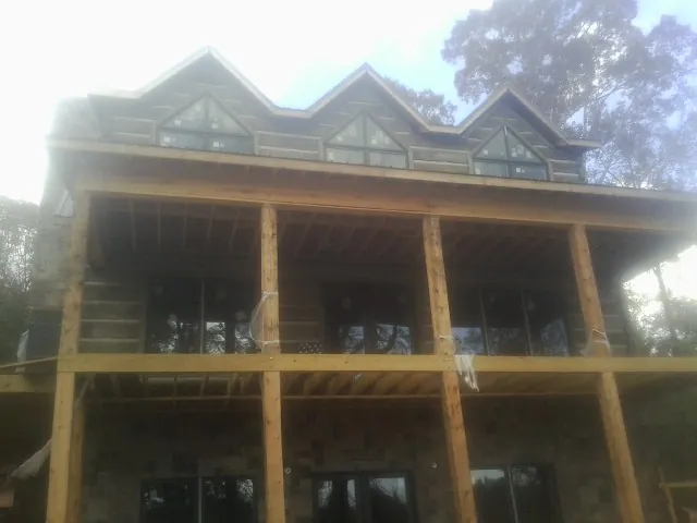Dormers and porch framing on a large log home under construction — Roof Coating work by our crew in Haswell