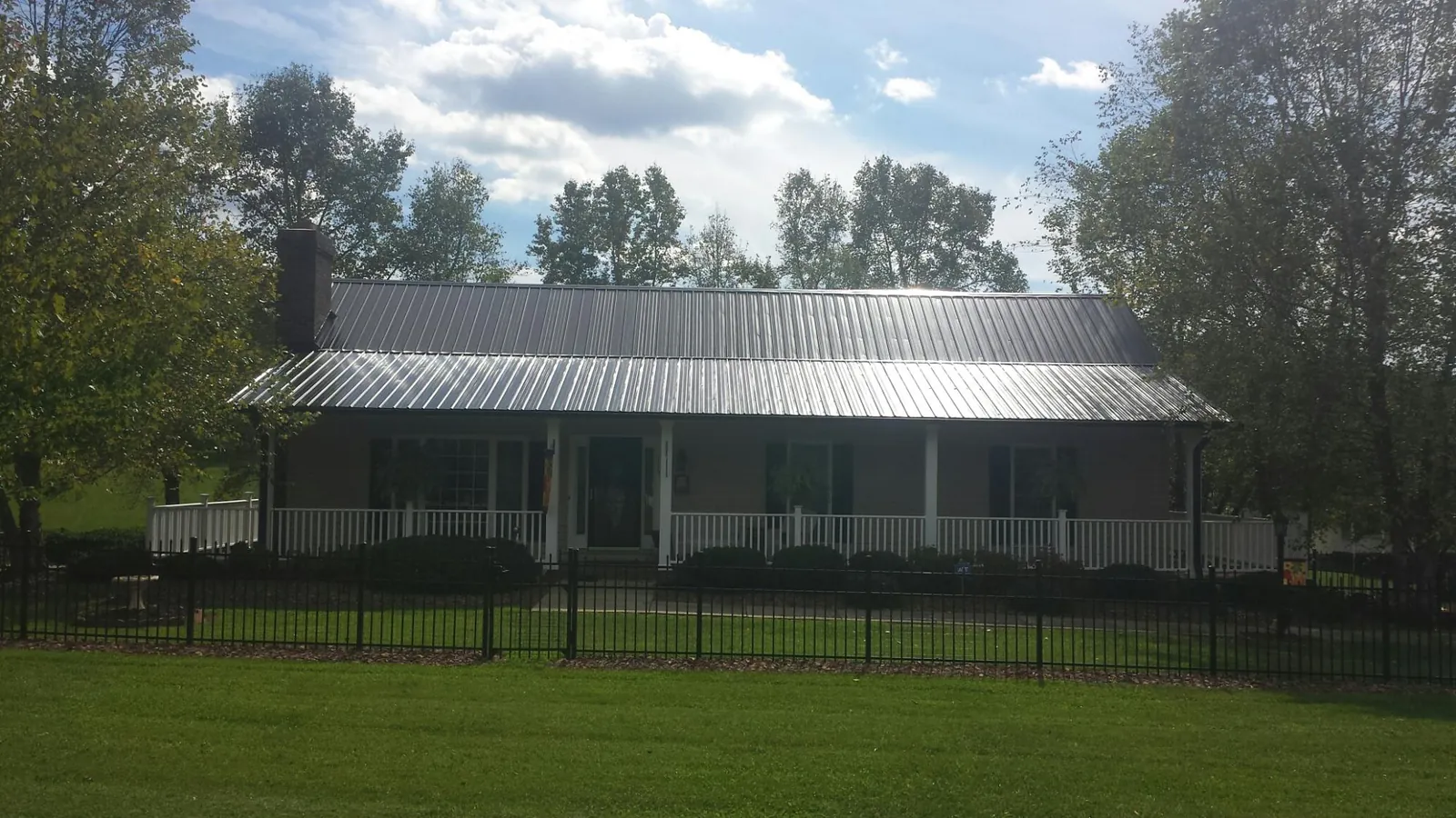 Gray metal roof on a brick ranch with a full width front porch — Gutter Guard Installation work by our crew in Haswell