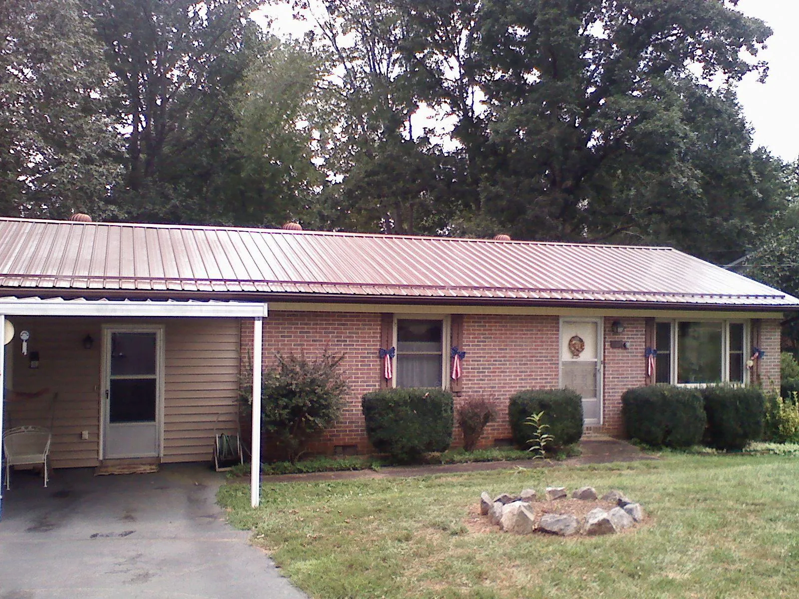 Bronze metal roof and carport on a brick ranch home — Roof Repair work by our crew in Haswell