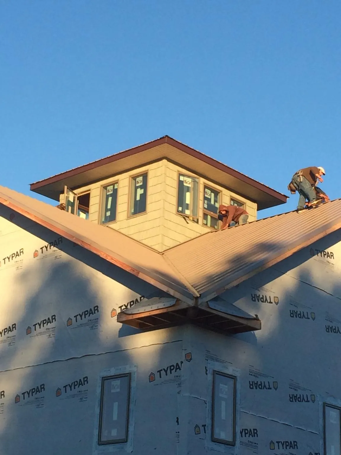 Roofers working around a rooftop cupola on a new metal roof at sunset — Roof Waterproofing in Haswell by Roofing Brothers